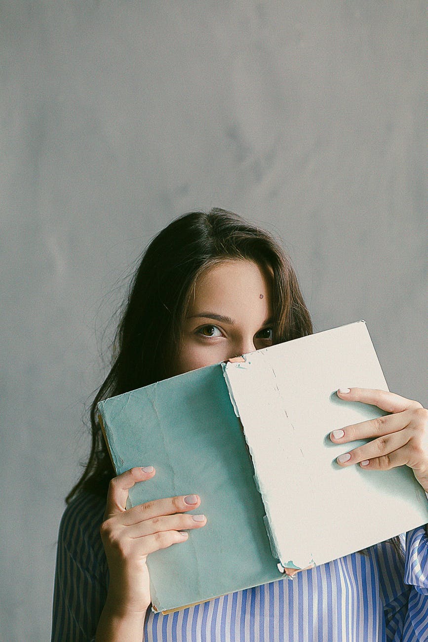 woman in blue striped flannel shirt holding a book indoors